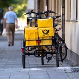 Ein Fahrrad von der Deutschen Post steht an einer Straße.