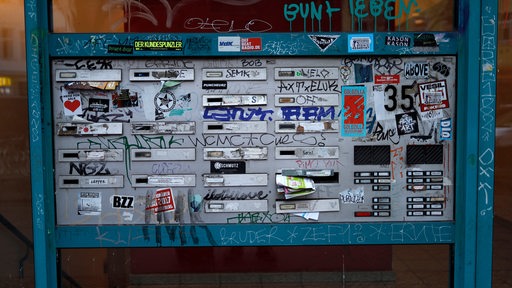 Graffitti und Aufkleber an einer Briefkastenanlage eines Wohnblocks