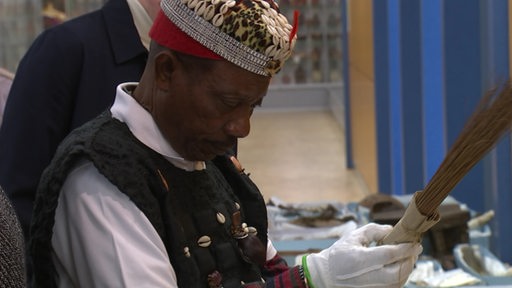 Ein Priester aus Ghana betrachtet ein Artefakt im Überseemuseum