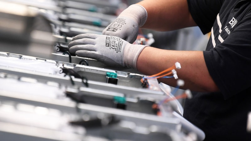 Ein Arbeiter mit Handschuhen montiert Waschmaschinen.