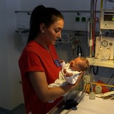 Eine Pflegerin hält ein Baby im Arm.