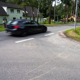 Auf einer Straße sind im Kreuzungsbereich Markierungen auf dem Boden zu sehen.
