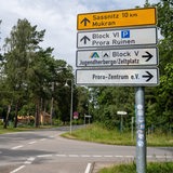 Straßenschilder stehen an einer Kreuzung, sie weisen unter anderem den Weg nach Sassnitz, Mukran und zu einer Jugendherberge.