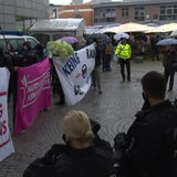 Mehrere Demonstrierende mit Schildern stehen gegenüber der Polizei in Delmenhorst, um gegen den Bürgerdialog der AfD zu protestieren.