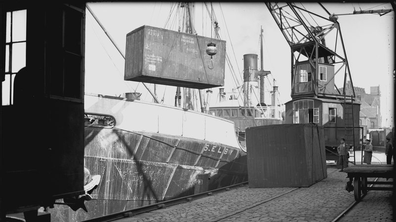 Ein Kran hebt einen Container auf ein Schiff.
