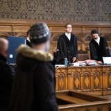 Angeklagte stehen bei Prozessbeginn im Gerichtssaal vor den Richtern.