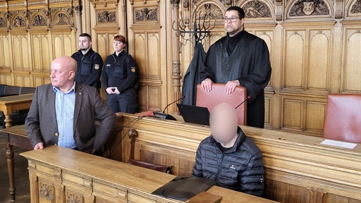 Bild zeigt den Gerichtssaal im Bremer Landgericht mit verpixeltem Gesicht des Angeklagten, der seinen Sohn erstochen haben soll.