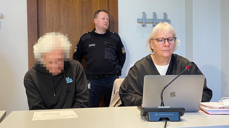 Ein Angeklagter (Gesicht verpixelt) sitzt neben seiner Anwältin im Gerichtssaal
