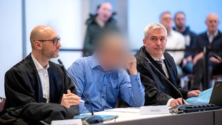 Der angeklagte technischer Kostenprüfer des Marinearsenals sitzt zwischen seinen Anwälten vor Prozessbeginn in der vom Landgericht Oldenburg genutzten Weser-Ems-Halle.