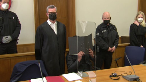 Der Angeklagte bedeckt sein Gesicht in der Gerichtsverhandlung vor dem Landgericht Oldenburg. 