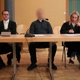 Ein Angeklagter und seine beiden Anwälte sitzen ein einem Tisch