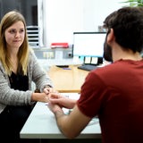 Eine junge Frau spricht in einer Flüchtlingsunterkunft mit einem Geflüchteten