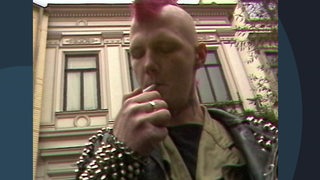 Archivbild: Ein Punk in Lederjacke und pinken Haaren zündet sich eine Zigarette an.