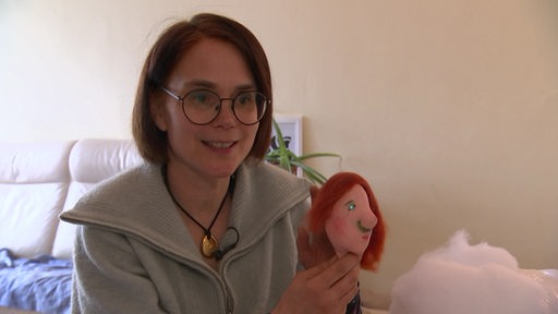 Es ist Julia Warneke, Theaterpädagogin, mit einer Puppe in der Hand zu sehen. 
