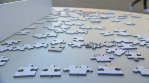 Auf einem Tisch liegen mehrere Puzzelteile verteilt.