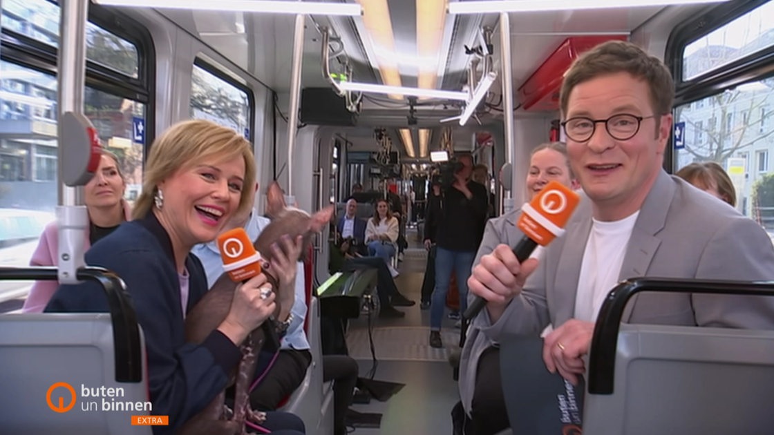 Kirsten Rademacher und Felix Krömer moderieren eine Sendung in einer Straßenbahn.