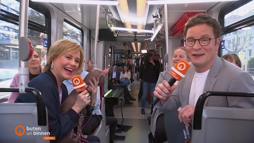 Kirsten Rademacher und Felix Krömer moderieren eine Sendung in einer Straßenbahn.