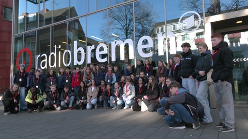 Eine große Gruppe Kinder und Jugendlicher posiert vor dem Radio Bremen Gebäude für ein Foto