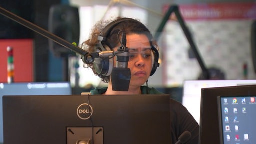 Eine Radio-Moderatorin sitzt vor einem Mikrofon.