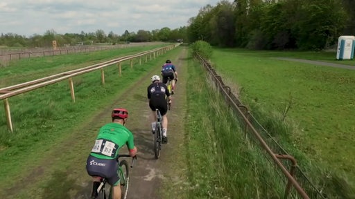 Auf der Bremer Galopprennbahn fahren drei Männer auf ihren Crossrädern entlang.