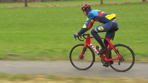 Radprofi Niklas Behrens am Rennrad fahren in der Natur.