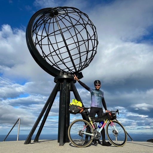 Extrem-Radsportler Florian Schigelski posiert triumphierend mit seinem Rad am Aussichtspunkt am Nordkap.