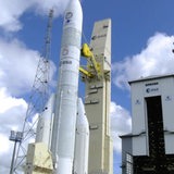 Die neue Ariane 6 Rakete steht startbereit an einem Turm.
