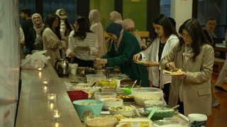 Mehrere Studierende der Uni Bremen bedienen sich an einem Buffet beim Fastenbrechen.