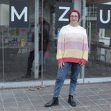 Eine Frau mit Kopftuch steht vor einem Gebäude