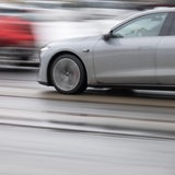 Ein graues Autos fährt auf einer Straße in der Innenstadt entlang,