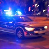 Ein Polizeiauto steht nachts auf einer Straße.