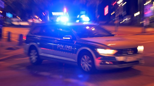 Ein Polizeiauto steht nachts auf einer Straße.