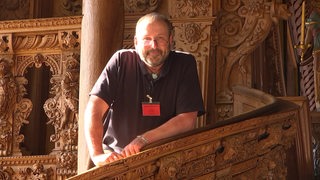 Möbelrestaurator Manfred Hübner auf einer Kanzel im Rathaus.