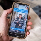 Hand hält ein Mobiltelefon auf dessen Display auf der Plattform TikTok ein Video des AFD Politikers Max Krah zu sehen ist, der Schüler dazu auffordert sich zur AFD zu bekennen.