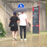 Ein Pärchen teilt sich einen Regenschirm und läuft am Schlachteufer entlang.