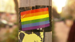 Die Regenbogenflagge als Sticker an einer Laterne.