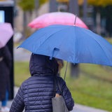 Eine Frau läuft mit einem Schirm durch die Innenstadt.
