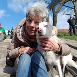 Eine Frau sitzt auf einer Treppe und hält ihren Hund im Arm
