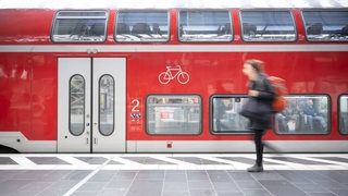 Eine Frau geht am Hauptbahnhof an einer Regionalbahn vorbei