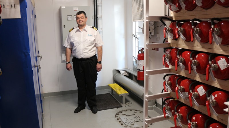 Ingenieur liyan Trayanov steht in einem Raum mit Feuerlöschern.