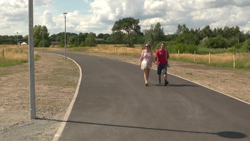 Zwei Personen gehen auf dem neuen Wegstück auf dem ehemaligen Rennbahngelände spazieren.