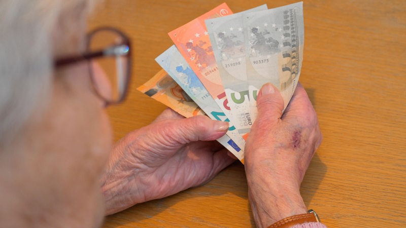 Eine alte Frau hält Geld in ihrer Hand