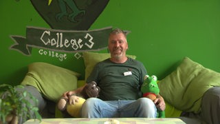 Resident Mentor Robert Rennie sitzt auf einem Sofa.