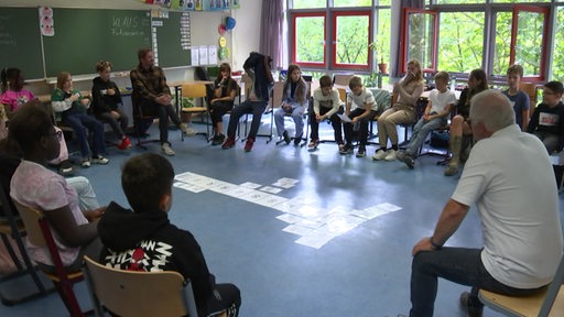 Respektcoaches sitzen im Stuhlkreis mit Schülerinnen und Schülern.