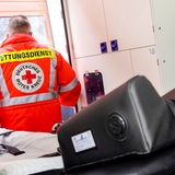 Ein Sanitäter mit einer Jacke des Deutschen Roten Kreuzes steht am Fenster eines Intensivstationszimmer in einem Krankenhaus. 