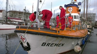 Mehrere Menschen auf einem historischen Rettungsboot im Vegesacker Hafen.
