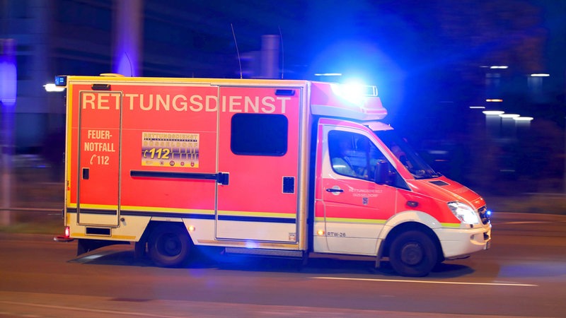 Ein Rettungswagen fährt über eine Straße mit Blaulicht.