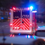 Ein Krankenwagen fährt mit Blaulicht durch dichten Verkehr.