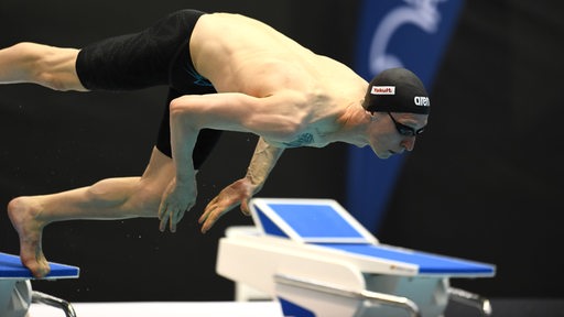 Schwimmer Florian Wellbrock stößt sich kraftvoll vom Startblock ab beim Sprung ins Becken.