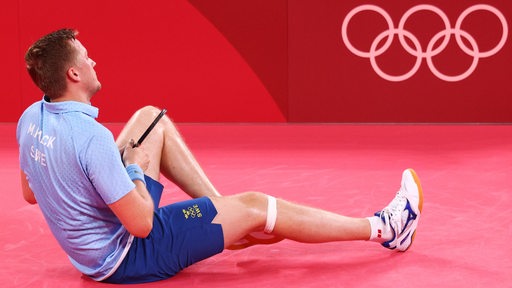 Tischtennis-Profi Mattias Falck bleibt nach einem Sturz im Olympia-Match auf dem Hosenboden sitzen.
